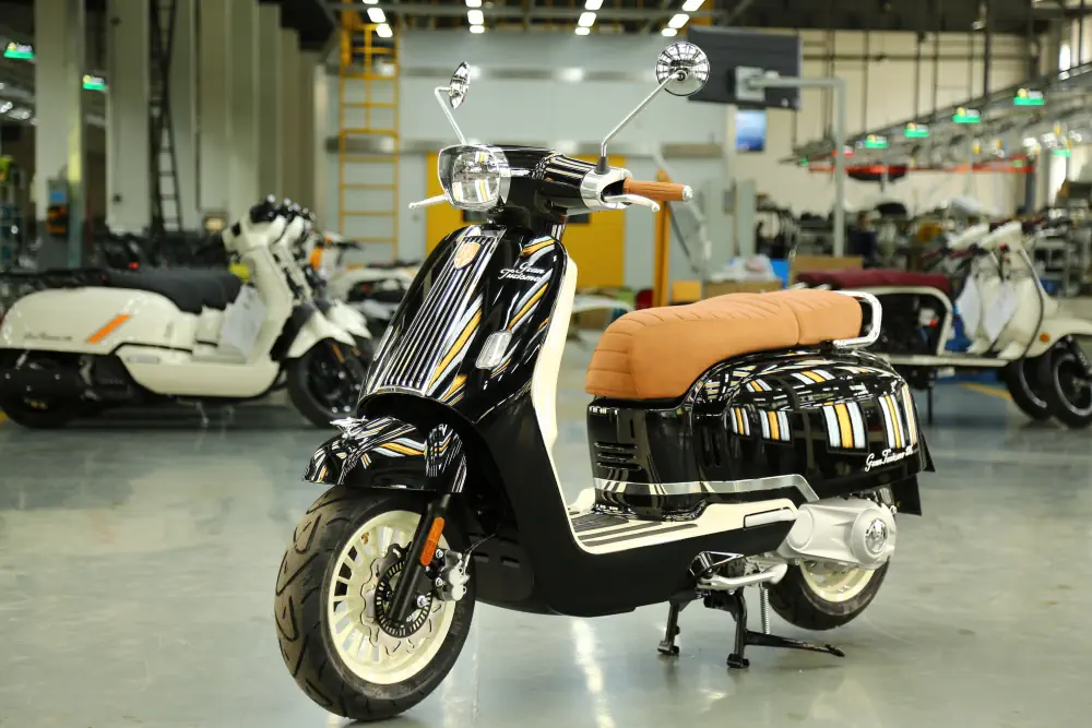 Ein schwarzer Retro-Roller von Royal Alloy mit braunem Sattel und modernen Chrom-Elementen steht in einer großen Halle.