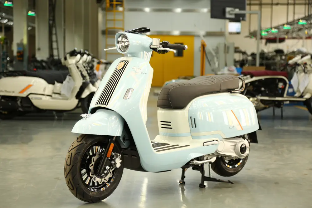 Ein hellblauer Royal Alloy Retro-Roller mit 125 ccm steht in einer Garage oder einem Showroom.